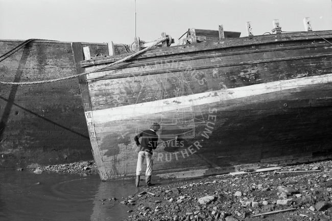 Man carrying out maintenance work on boat, 1978.