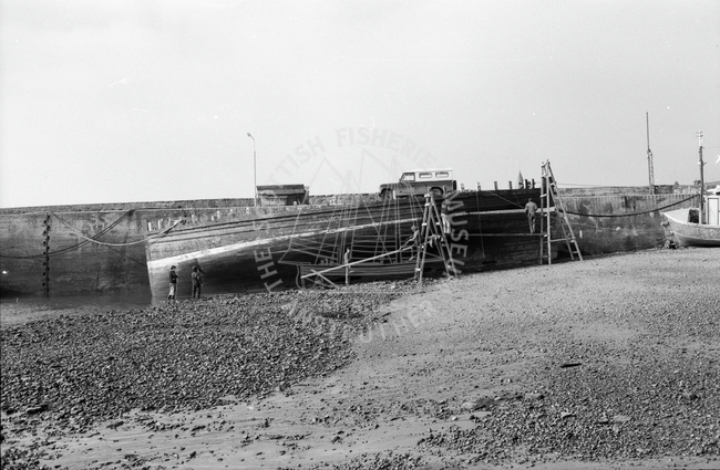 Boat undergoing maintenance in harbour, 1978.